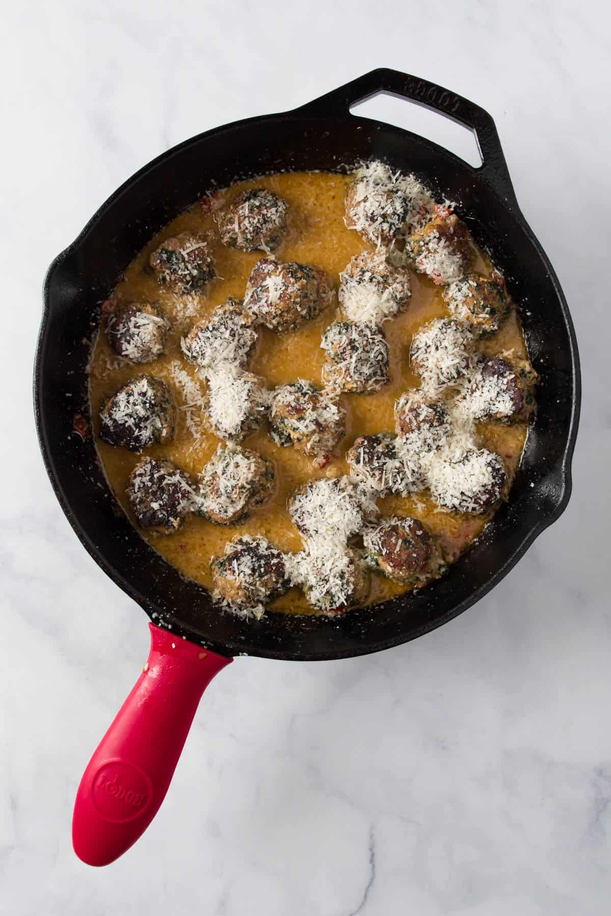 Veggie turkey meatballs in cream sauce simmering and finished with parmesan cheese.