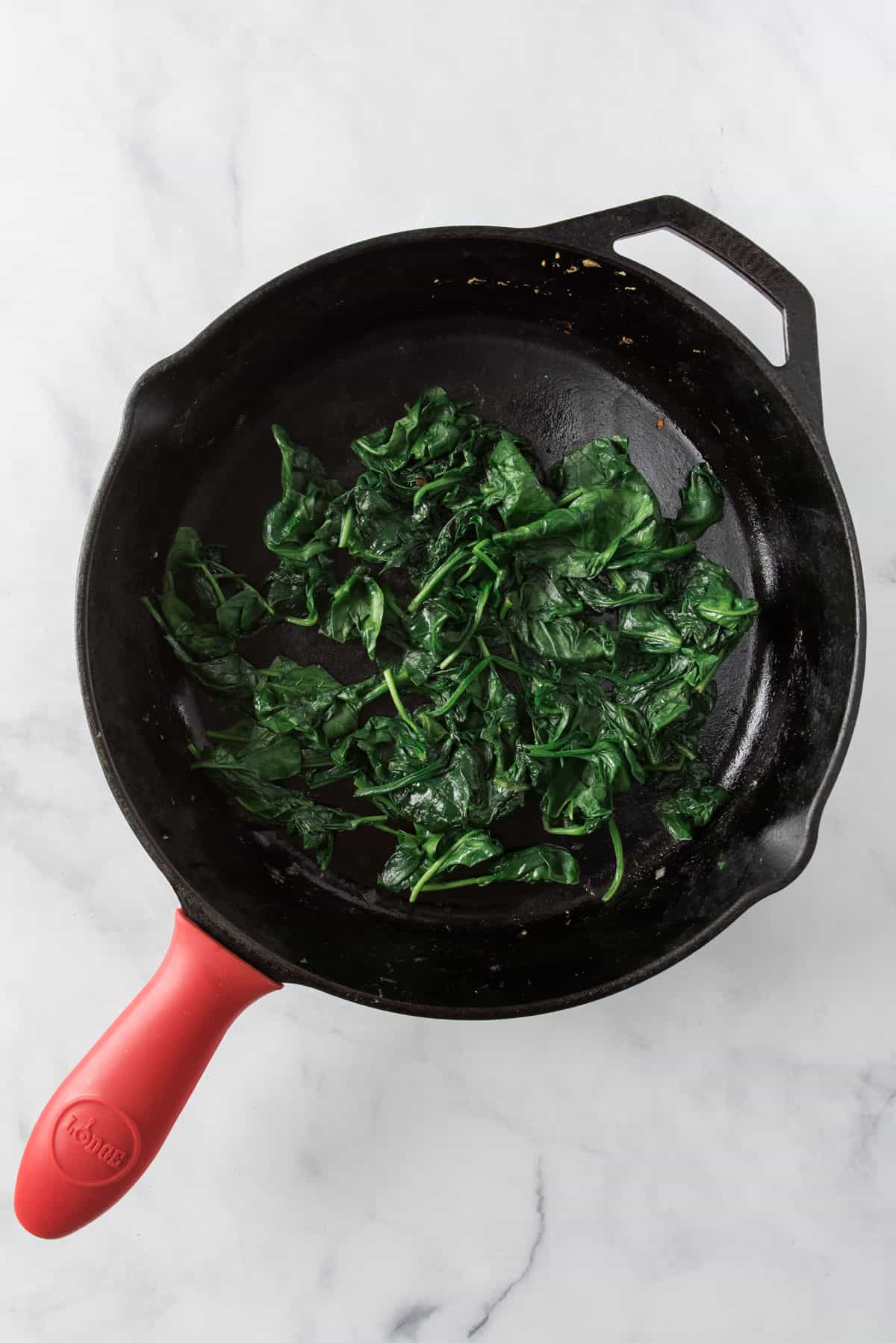 Veggie turkey meatballs in cream sauce, sautéing spinach with shallot in a cast iron skillet.