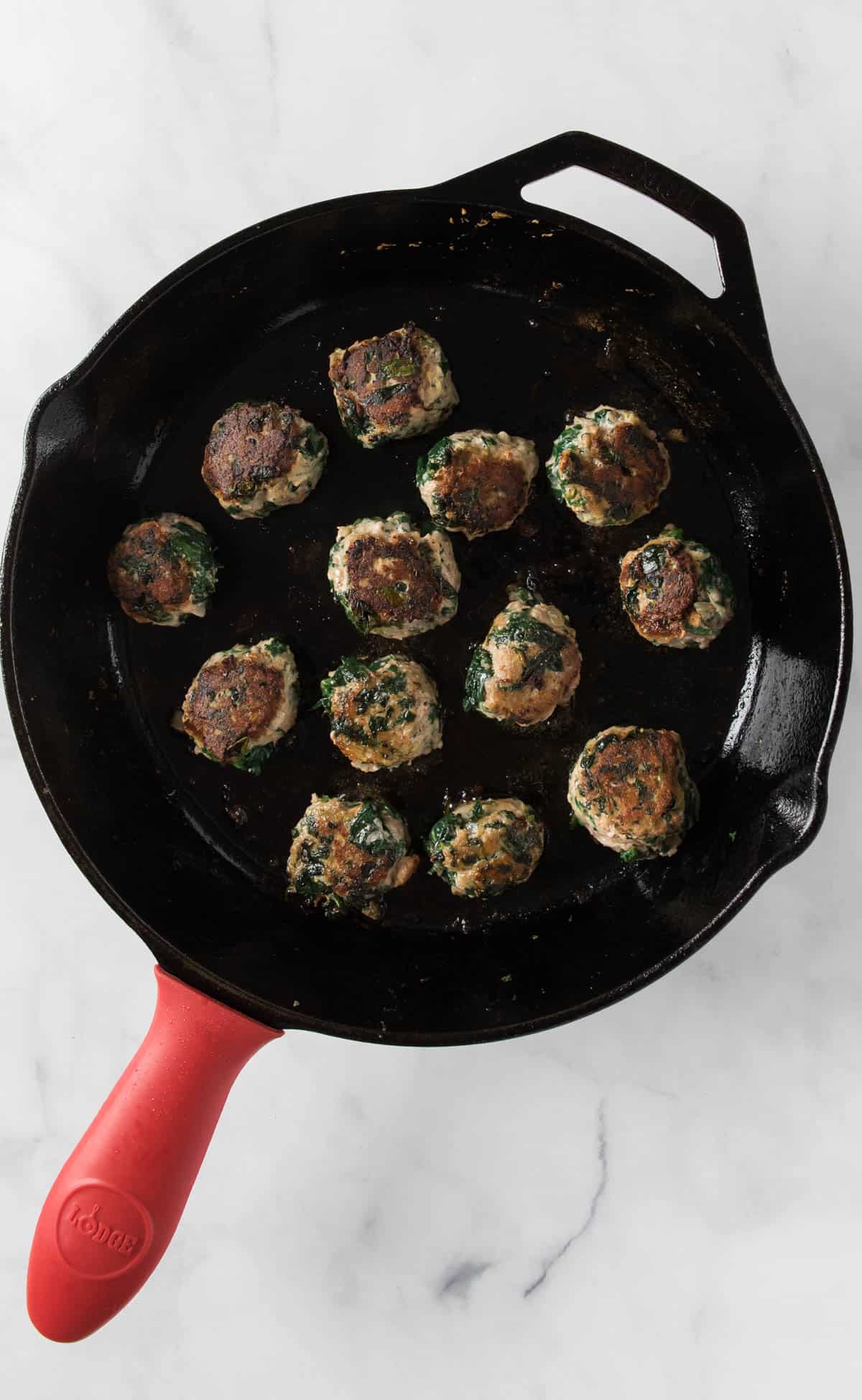 Veggie Turkey Meatballs browning in a cast iron skillet.
