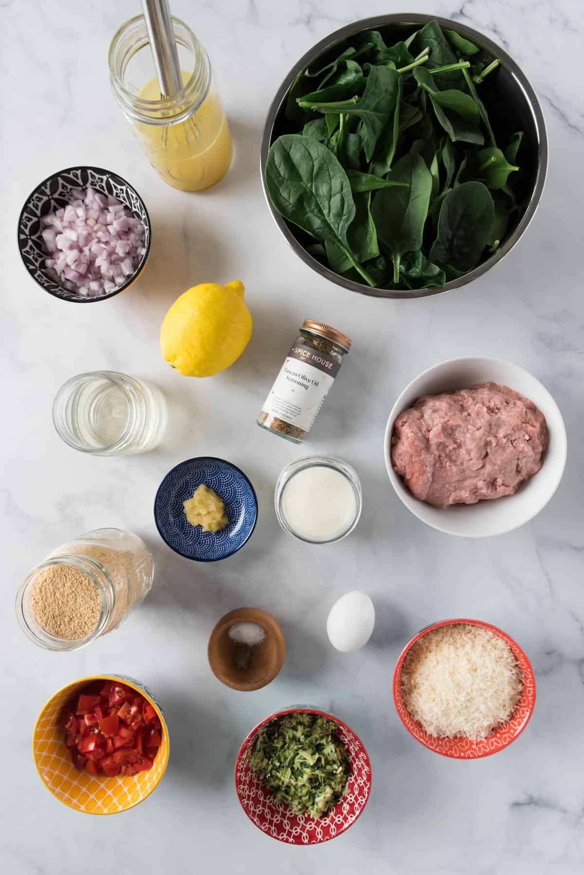 Ingredients for veggie turkey meatballs in cream sauce laid out on a white marble background in various bowls and jars.