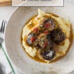 Veggie turkey meatballs over creamy mashed potatoes in a large shallow ceramic bowl with a fork, napkin and parmesan cheese on the side.