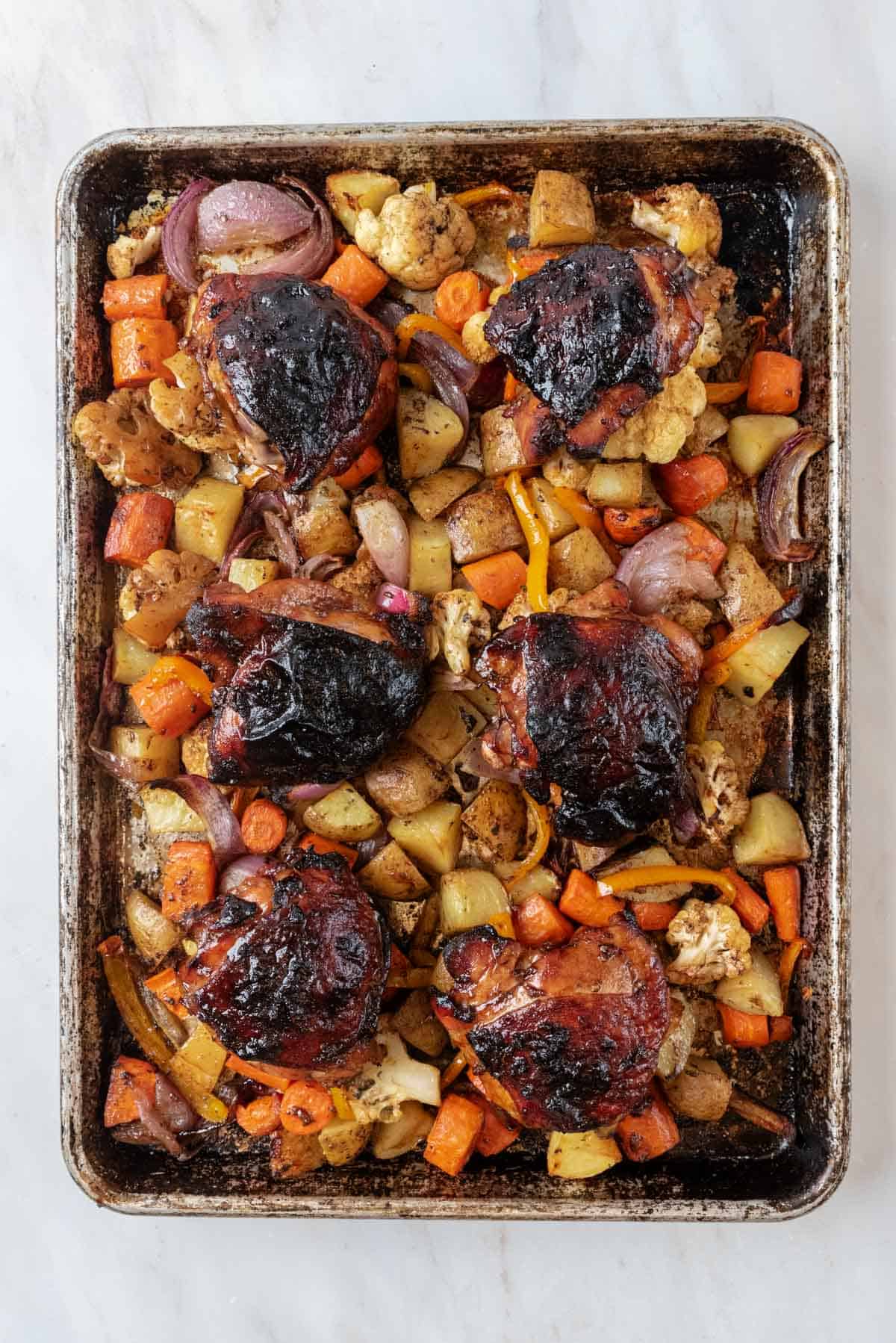 Fresh from the oven, roasted chicken thighs and vegetables on a large sheet pan.
