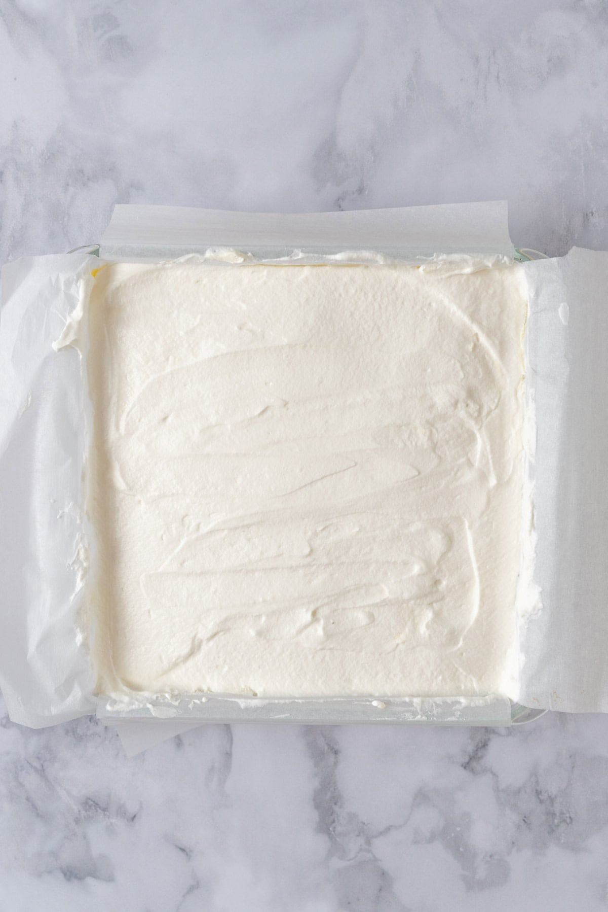 An assembled Lemon Lush Dessert in a 9x9 pan, ready for refrigeration.