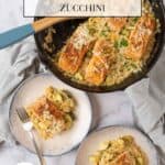 A cast iron skillet holding Salmon Orzo, garnished with parmesan cheese and chives, a grey linen napkin on the handle. Two shallow bowls holding a serving of salmon and pasta sit beside the skillet.