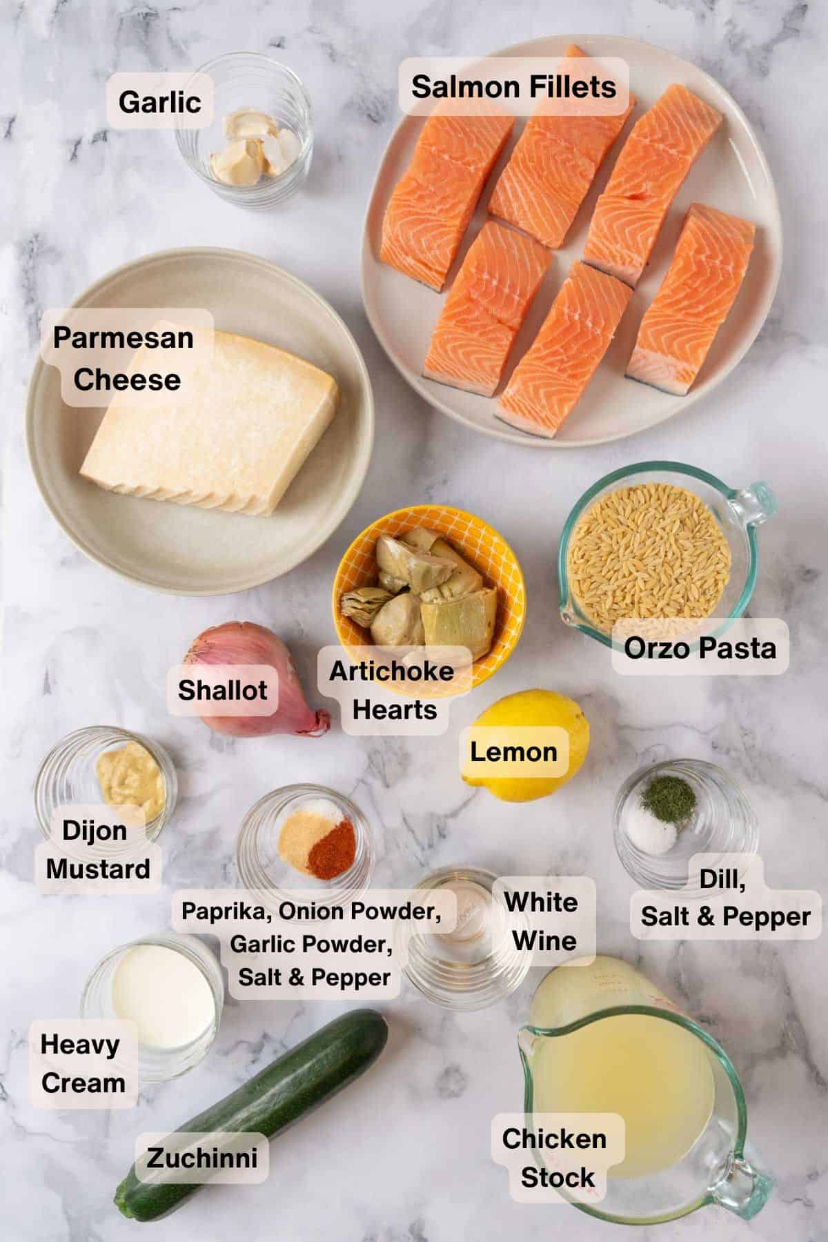 Ingredients for One Pan Salmon Orzo labeled in various bowls and containers on a white marble background.