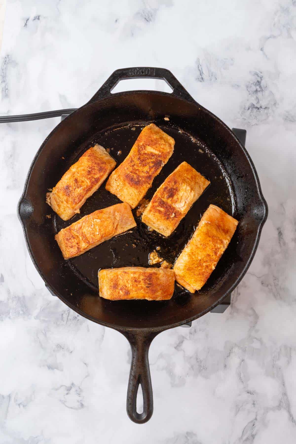 Seared salmon fillets in a cast iron skillet.