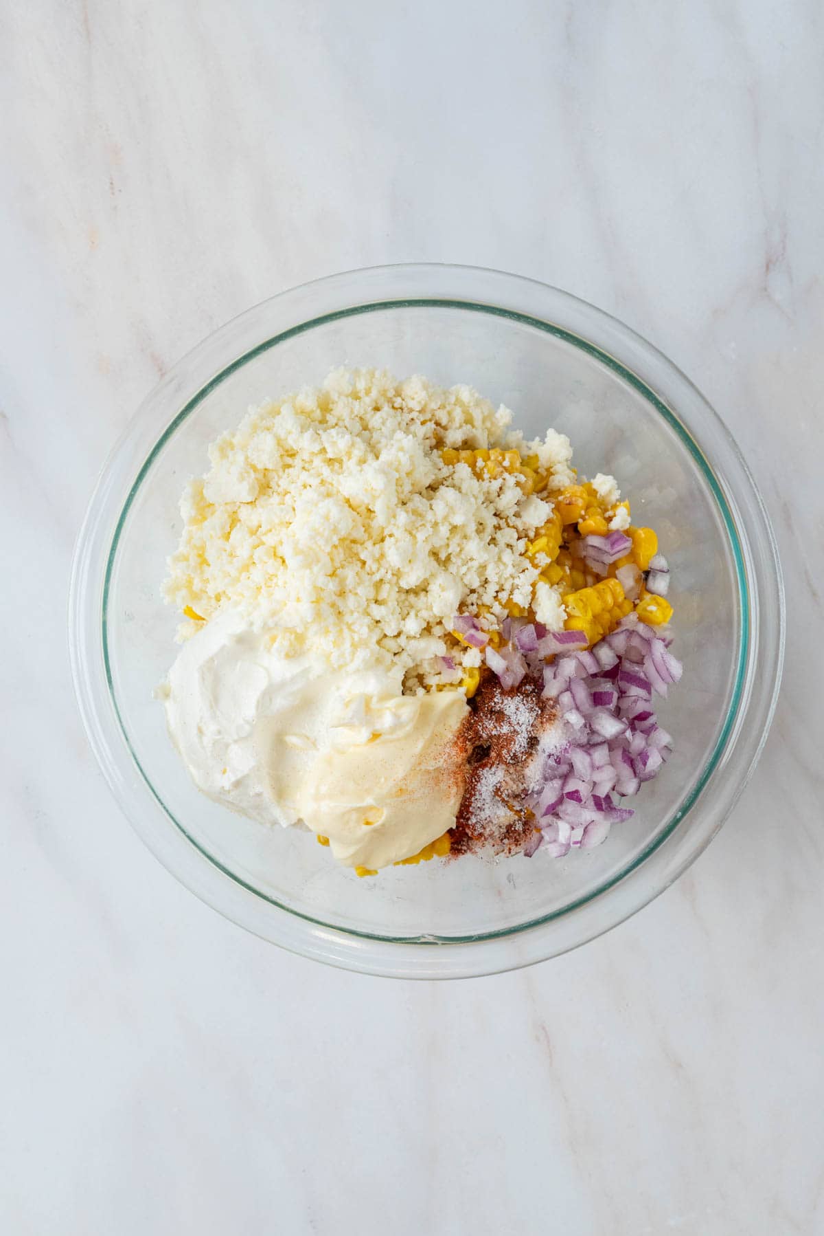 Ingredients for corn salad in a glass mixing bowl.