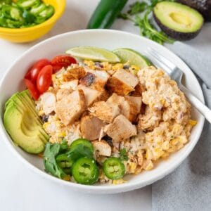 A shallow white bowl filled with Mexican Street Corn Chicken * Cilantro Lime Rice Bowls with bright garnishes.