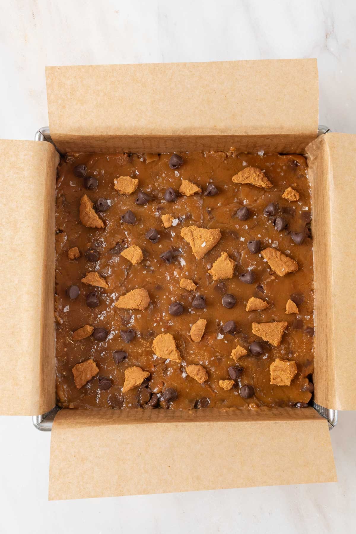 Raw Biscoff blondie batter in a baking pan, ready to be placed in the oven.