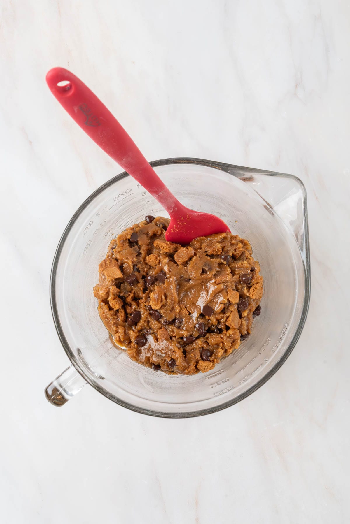 Biscoff blondie batter mixed together in a clear glass mixing bowl, ready to be placed into a baking pan.