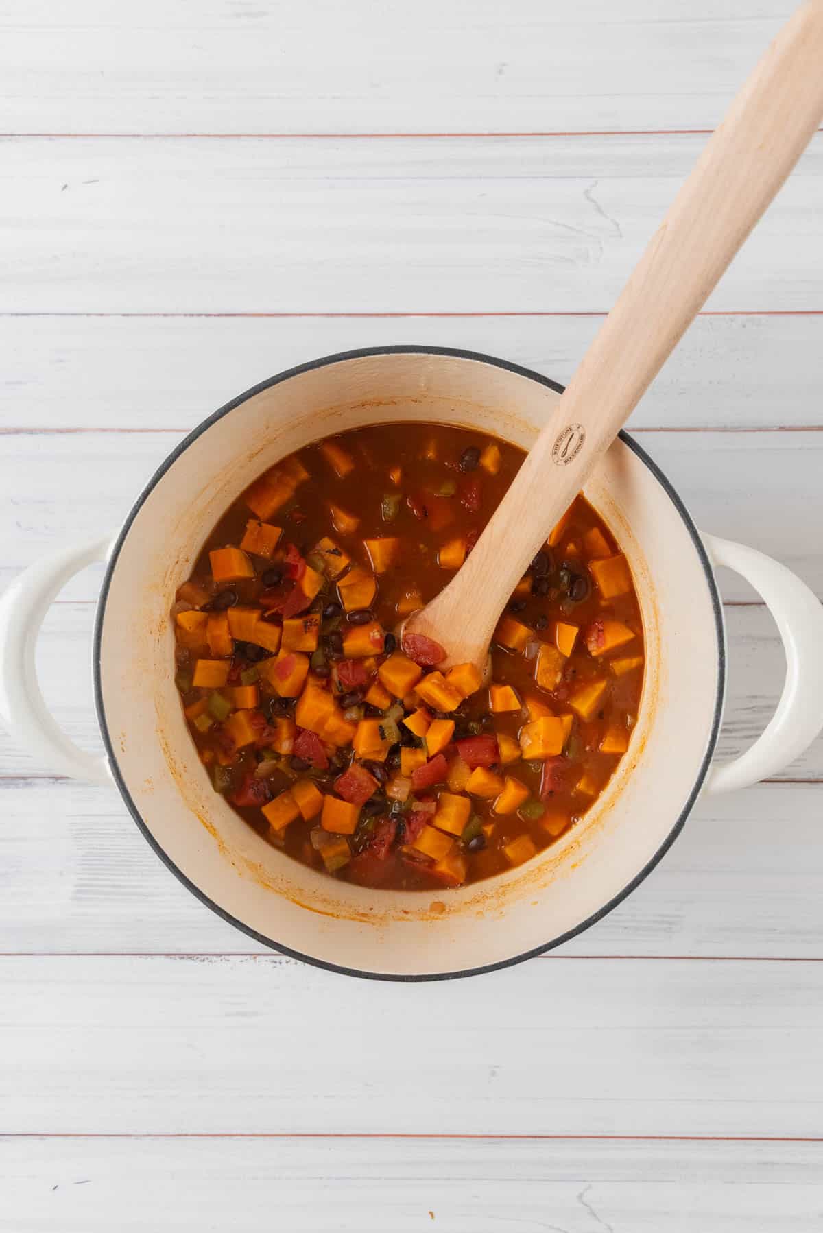 Sweet potato black bean soup cooking in a white Dutch oven before being pureed.
