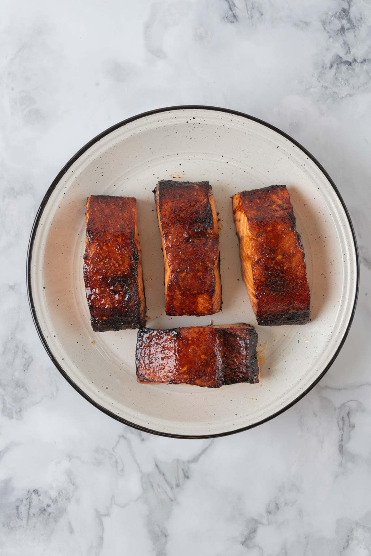 Hot honey glaze salmon fresh from the air fryer, resting on white and black speckled serving platter.