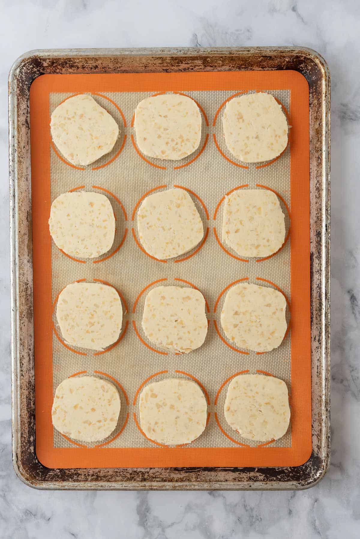 Raw cookie dough cut and placed on a baking sheet.