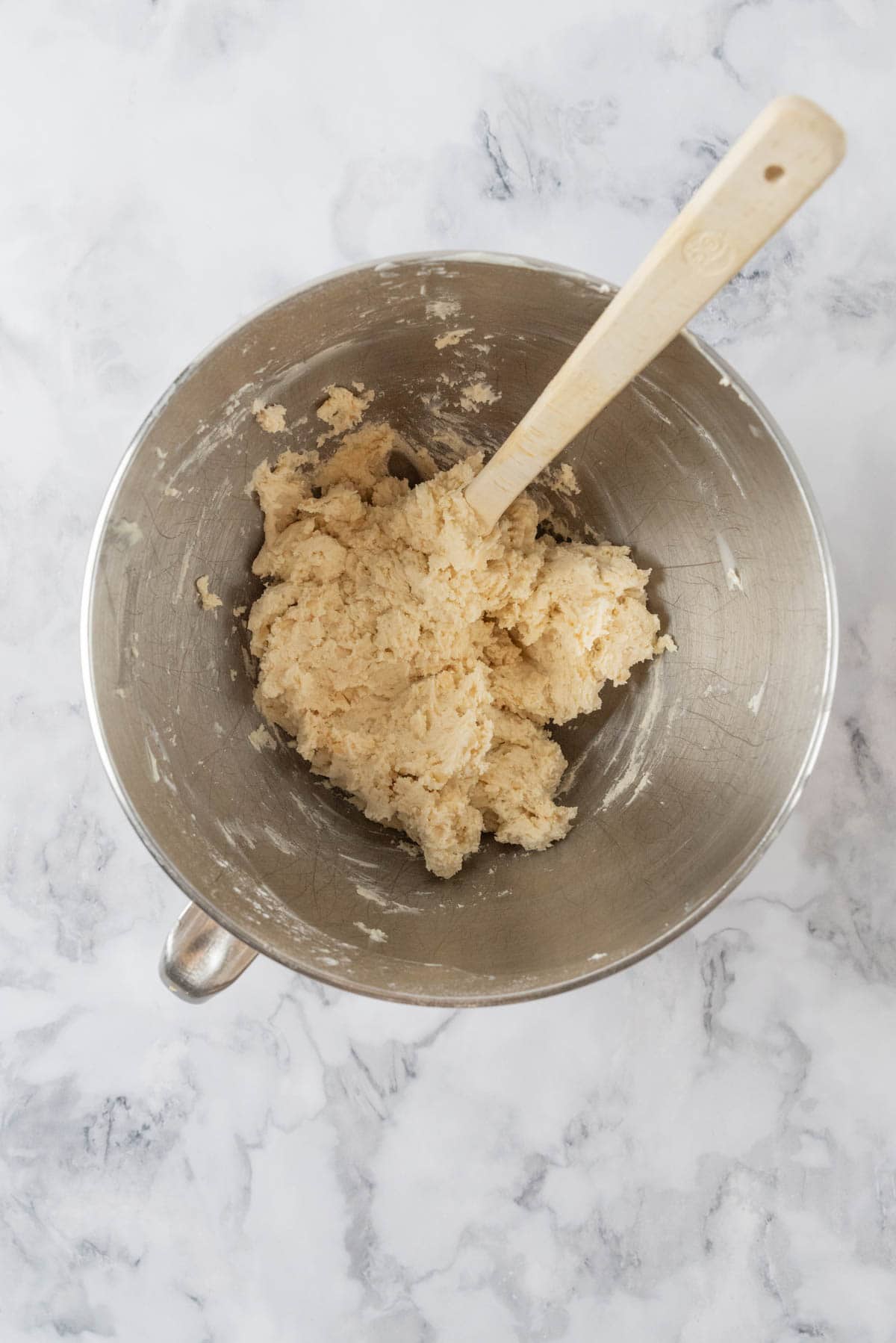 Macadamia nut shortbread cookie dough mixed together in a mixing bowl with a spatula.