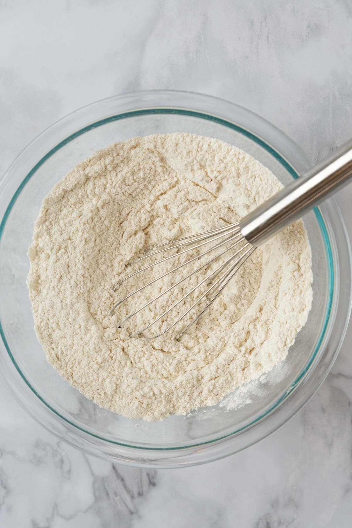 Dry cookie ingredients whisked together in a glass mixing bowl.
