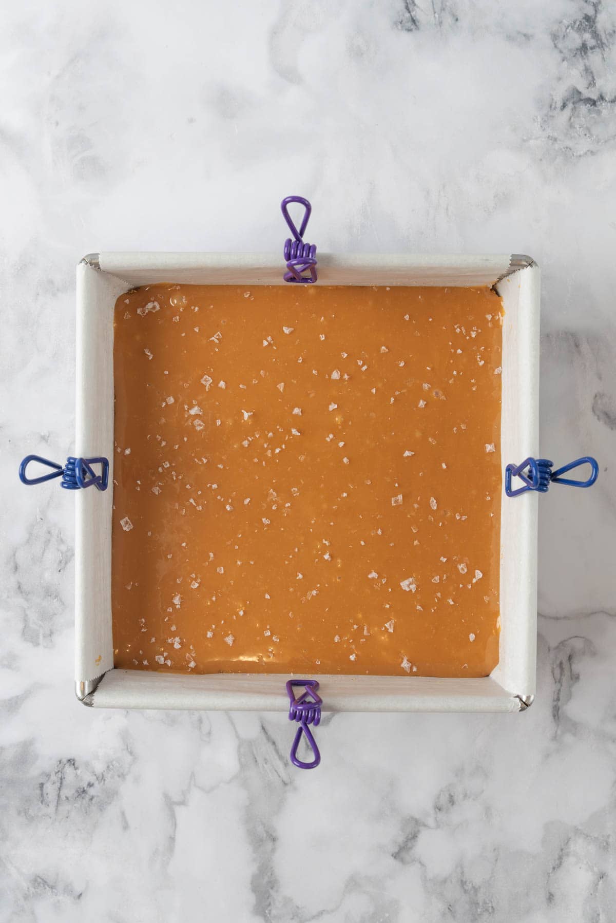 Caramel layer spread evenly in the 8x8 pan with flaky seas salt scattered on top.
