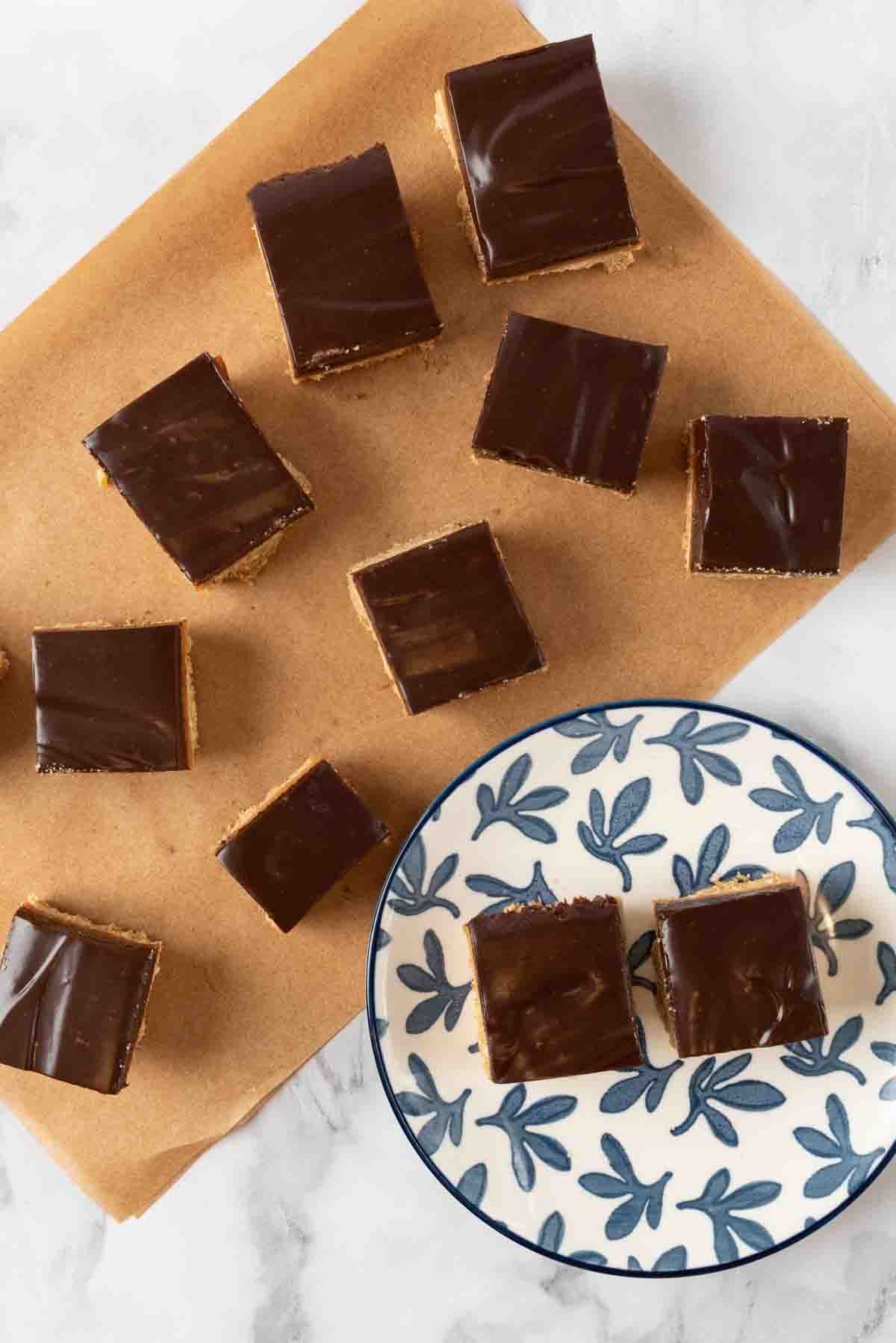 Chocolate espresso bars cut and plated on a blue and white plate with more to the side, scattered on a sheet of brown parchment paper.