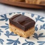 A closeup of a chocolate espresso bar on a white plate with delicate blue leaves. A wooden serving platter in the background.