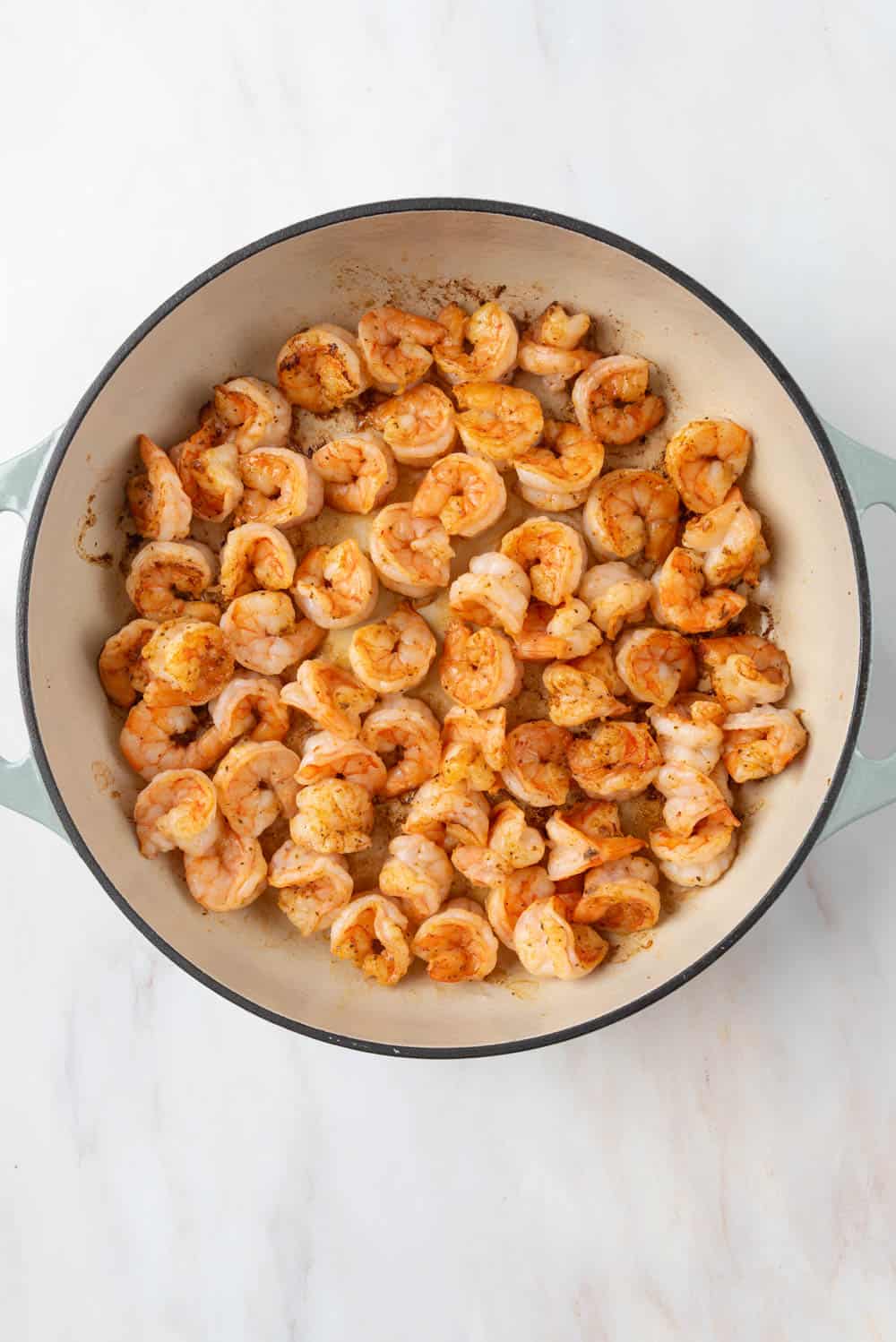 Shrimp seasoned with Old Bay searing in a hot braising pan.