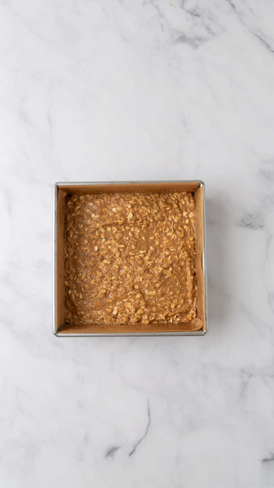 Breakfast bar batter poured into an 8x8 pan, ready to be put in the oven and baked.