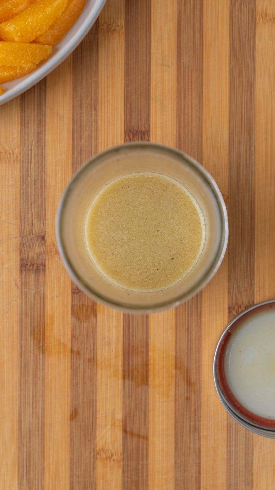 A mason jar with citrus vinaigrette resting on a wooden cutting board.
