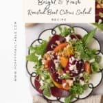 A gorgeous plate of colorful beet and citrus salad with feta cheese sits in the middle with a gold fork and linen napkin resting to the side. A huge platter filled with salad sits above the serving plate.