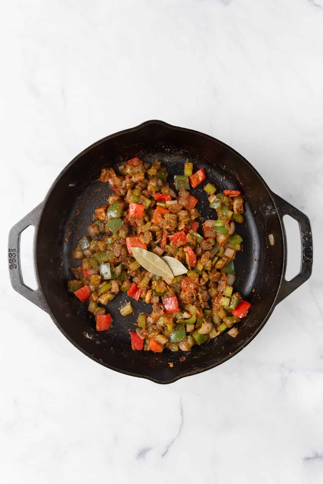 Bay leaves added to sautéed aromatics cooked with flour and seasonings in a cast iron skillet.