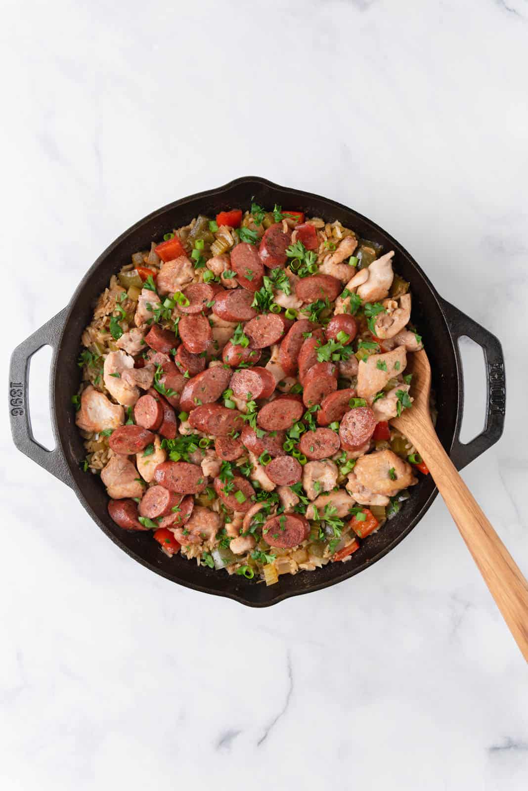 A skillet filled with chicken dirty rice, garnished with parsley and green onions, ready to serve.