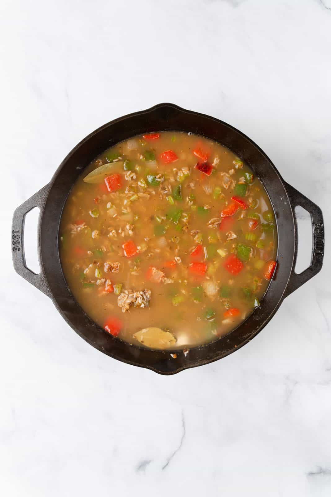 Chicken stock poured into the pan of aromatics, seasonings and rice.