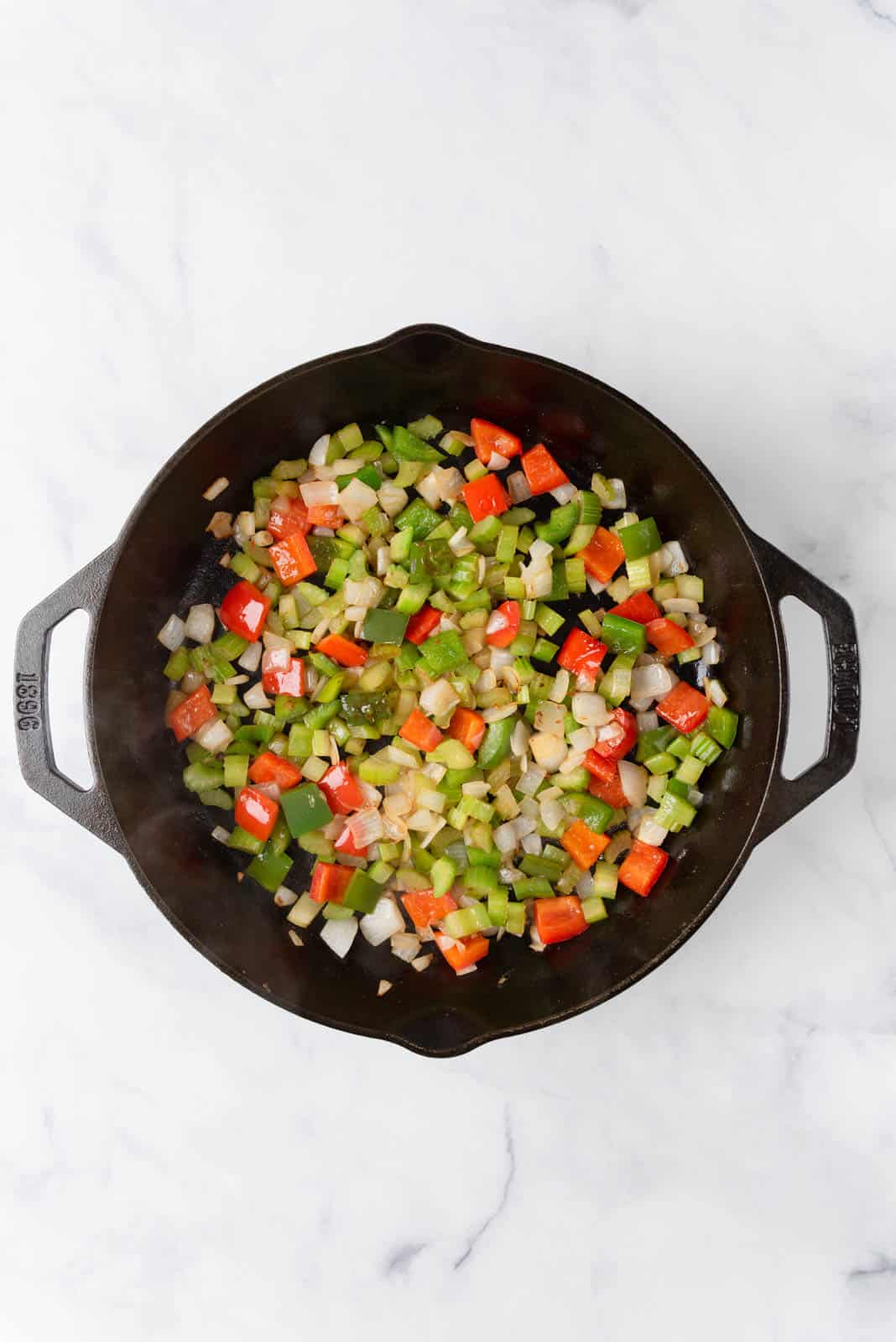Trinity of aromatics sautéing in a cast iron skillet.